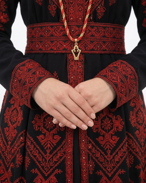 Alhaifawi | Traditional black and red embroidered garment with a decorative belt and pendant.