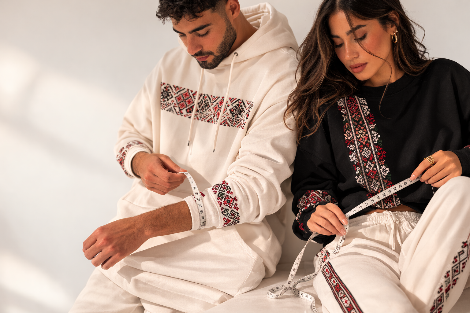 Alhaifawi | Two people wearing embroidered traditional outfits sitting together.